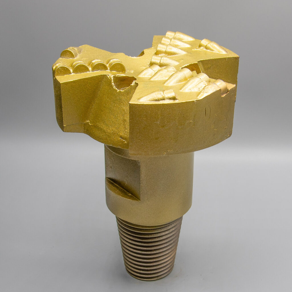 Goldfarbener Industriebohrer mit abgewinkelten Schneidkanten und Gewindesockel, abgebildet vor einem schlichten Hintergrund.